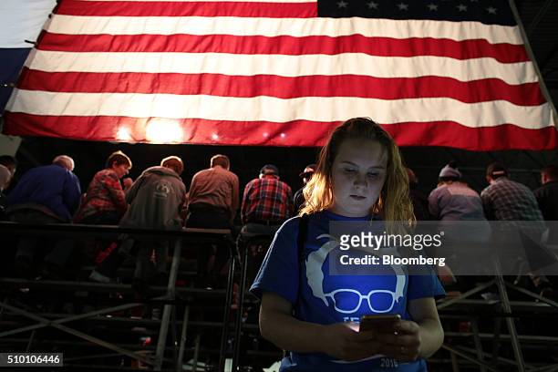 An attendee is illuminated by the screen of a smartphone at a campaign event for Senator Bernie Sanders, an independent from Vermont and 2016...