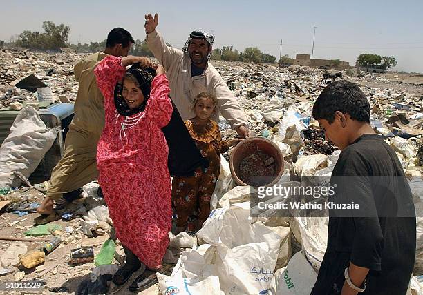 An Iraqi family living in a trash scavenge the rubbish around her home June 30, 2004 in Baghdad, Iraq. Dozens of Iraqi families continue to live...