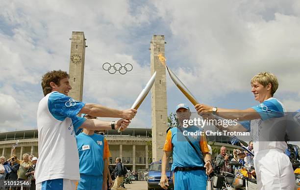 Samsung torchbearer Andreas Franke receives the Olympic Flame from Rosemarie Ackermann at the launch site outside the Olympic Stadium during the...