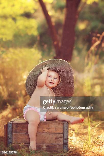 baby girl wearing pearls and a big floppy hat - eenjarig plantenkenmerk stockfoto's en -beelden