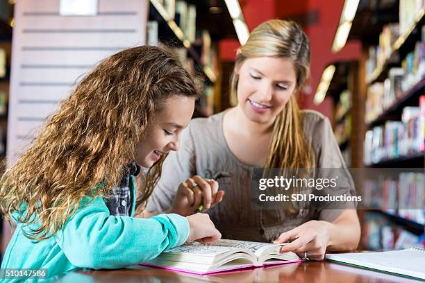 kleines mädchen lesung homeschool aufgabe zu mutter, die hausaufgaben in der bibliothek - library　woman stock-fotos und bilder