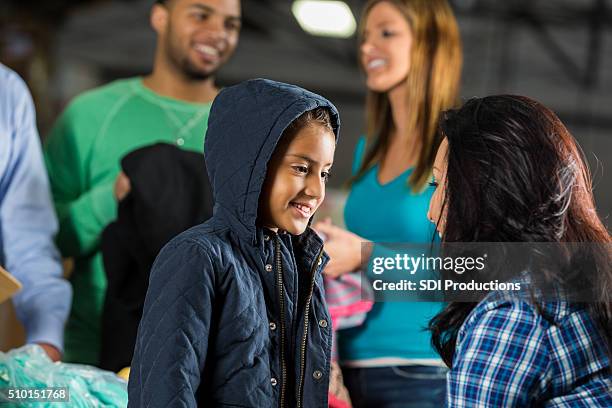 little girl receives coat at charity clothing drive - child winter coat stock pictures, royalty-free photos & images