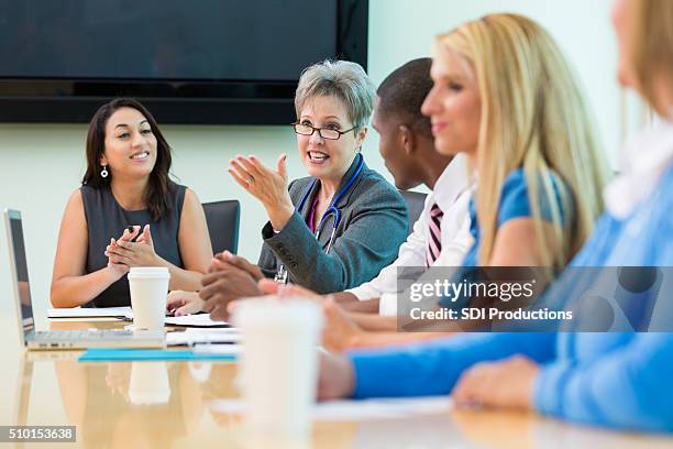 senior doctor speaks in hospital board meeting - policies and procedures stock pictures, royalty-free photos & images