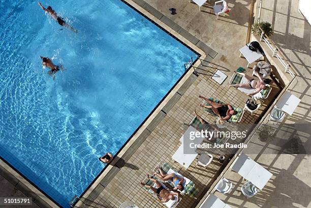 People enjoy the pool at the Al Hamra hotel July 1, 2004 in Baghdad, Iraq. A defiant Saddam Hussein apeared in Iraqi court July 1 and rejected...