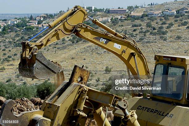 An Israeli contractor's Caterpillar 330B LME hydraulic excavator grabs a load of soil and rocks as it and a Caterpillar bulldozer clear the path of...