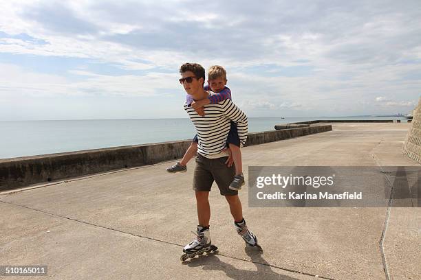 brothers piggyback - promenade stock pictures, royalty-free photos & images