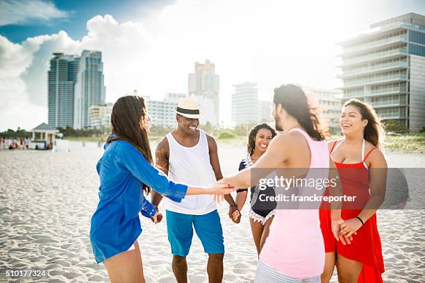 group of friends holding hands on the beach - lens flare young people dancing on beach stock pictures, royalty-free photos & images