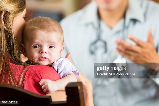 mother holding baby with cystic fibrosis during pediatric appointment - doctor looking at camera stock pictures, royalty-free photos & images