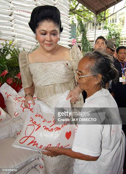 Former first Lady Imelda Marcos hands sacks of rice to squatter families as she marked her 75th birth anniversary in Manila 02 July 2004. Meanwhile...