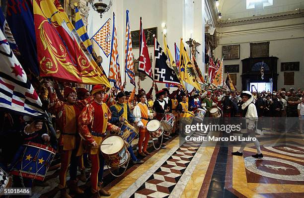 The standard bearer of the seventeen contrade, hold their flags inside the Basilica of Provenzano during the procession to pay their respect to the...