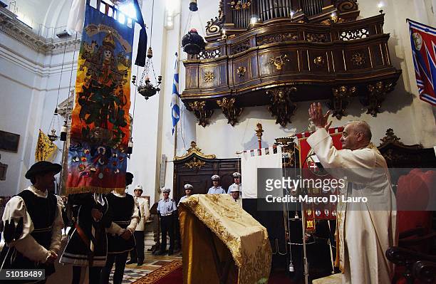 Priest blesses the Palio in the Basilica of Provenzano during the procession of the standard bearer to pay respect to the Madonna di Provenzano to...