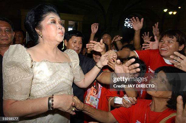 Former first lady Imelda Marcos blows a kiss to supporters from Manila's slum district of Tondo on her arrival at the Manila cathedral 02 July 2004...