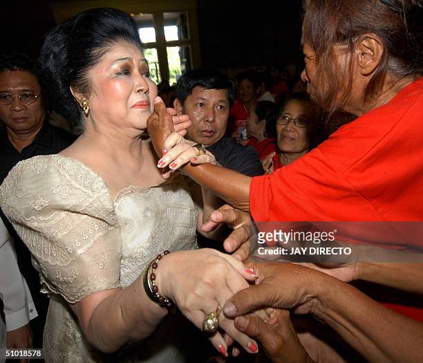 Residents of Manila's slum district of Tondo greets former first lady Imelda Marcos at the Manila cathedral 02 July 2004 where she attended a...