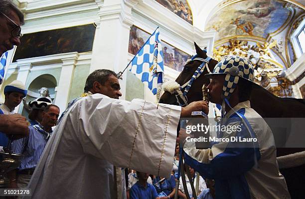 The jockey and the horse of the Onda one of the seventeen contrade or neighborood, are blessed by the priest of the Wave, before the Palio horse...