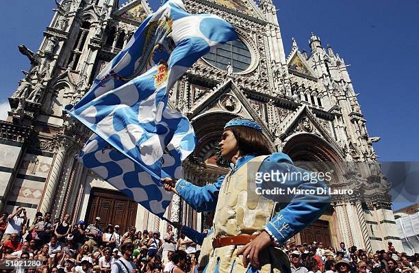 Two standard bearer belonging to the Onda one of the seventeen contrade, performs the flag waving display in front of the Cathedral of Siena before...