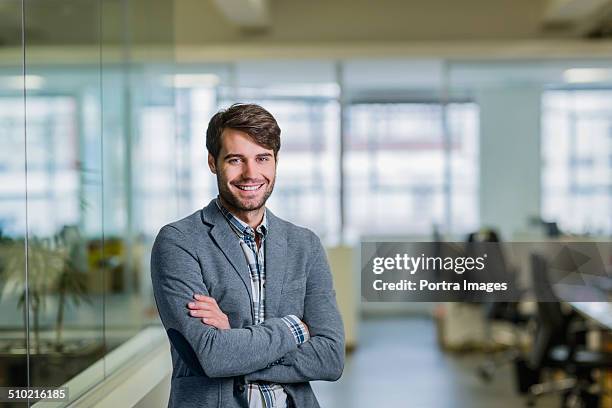 happy businessman standing arms crossed in office - mise au point sélective photos et images de collection