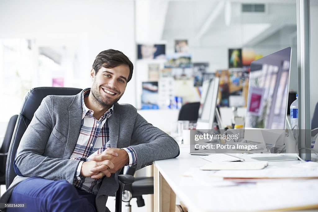 Happy businessman sitting at desk in office