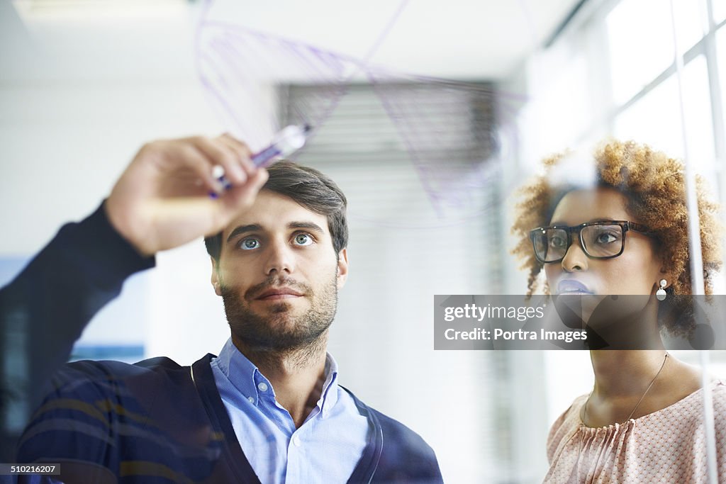 Business people drawing pie chart on glass wall