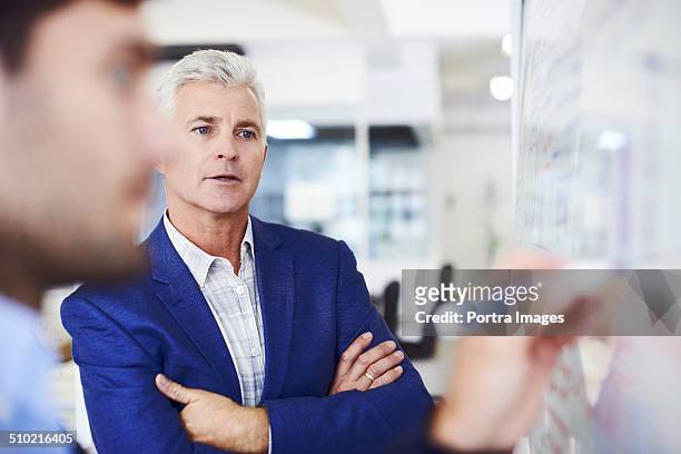 businessman with colleague writing on whiteboard - corporate portraits depth of field stock pictures, royalty-free photos & images