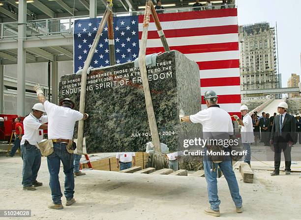 Construction workers move the cornerstone for the new Freedom Tower into place during the ceremony at the World Trade Center site July 4, 2004 in New...
