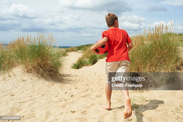 child having fun at the beach - boy barefoot rear view stock-fotos und bilder