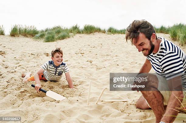 family playing ball game at the beach - cricket game fun stockfoto's en -beelden