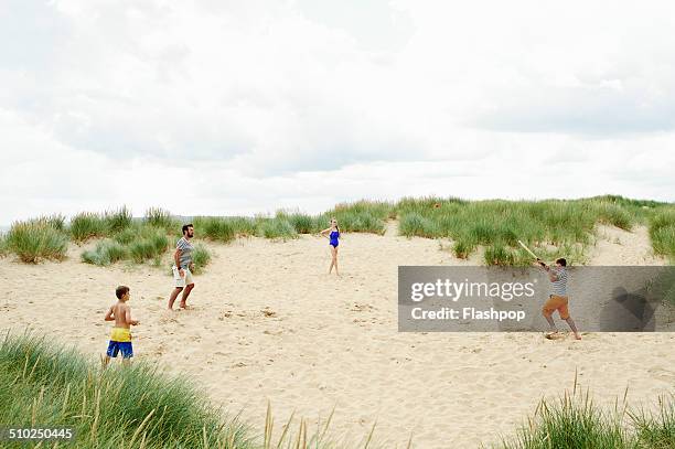 family playing ball game at the beach - cricket game fun stockfoto's en -beelden
