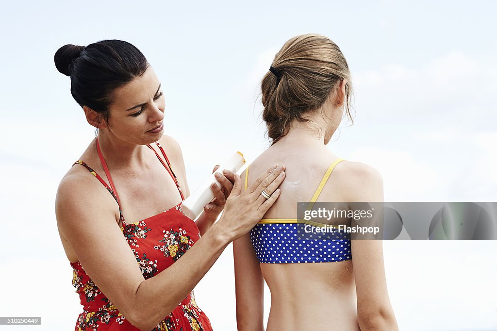 Mother applying sun cream to daughter's skin