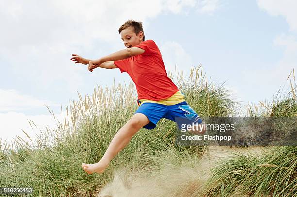 child having fun at the beach - rode korte broek stockfoto's en -beelden