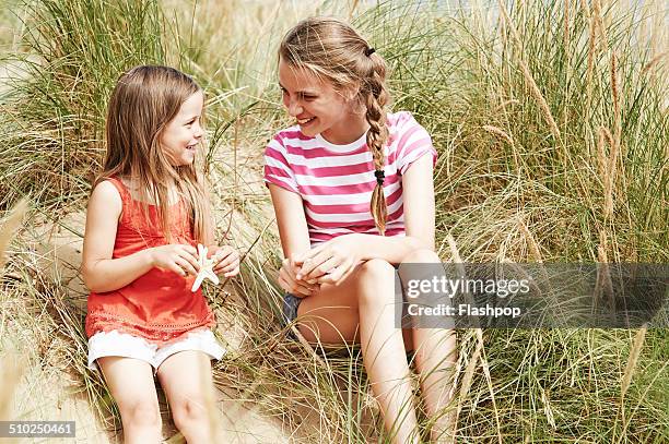 two sisters relaxing at the beach - sand dune stock pictures, royalty-free photos & images