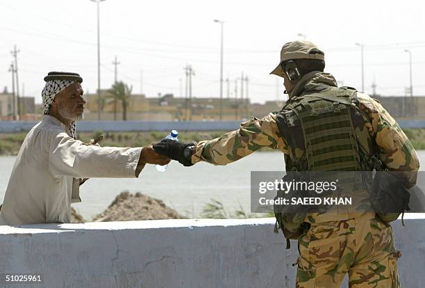 An Italian soldier gives a bottle of cold mineral water to an Iraqi Shiite Muslim man as he patrols the town of Nassiriyah, 375 kms southeast Baghdad...