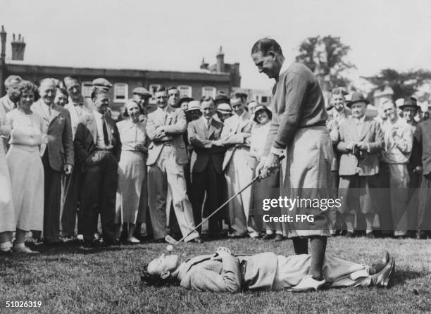 Australian golfer Joe Kirkwood tees off from a caddy's mouth, circa 1930.