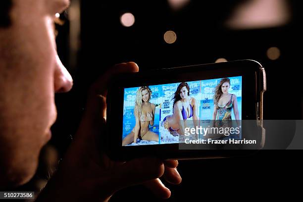 Photo professional views the historic three covers of 2016 Sports Illustrated Swimsuit Issue on a smart phone on the streets of Midtown Manhattan on...