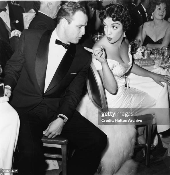 American actor Marlon Brando turns to face Mexican actor Katy Jurado , who gestures at him during a formal awards dinner, 1950s.