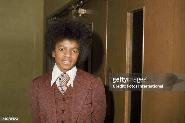 American pop singer Michael Jackson wears a brown suit, standing backstage at an event, January 19, 1974.