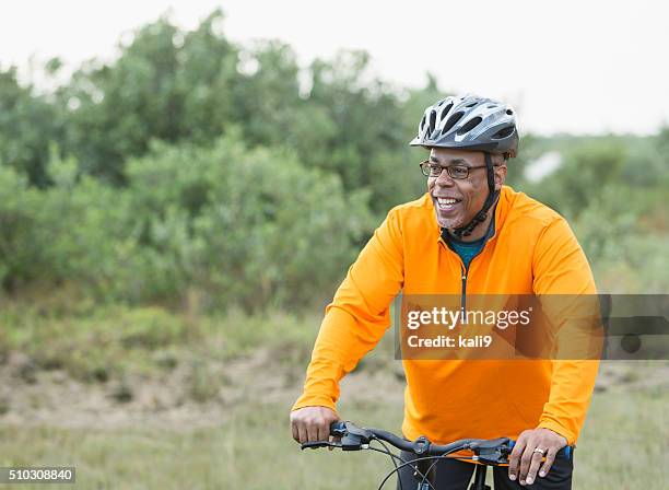 african american man riding bike in park - cycling helmet stock pictures, royalty-free photos & images