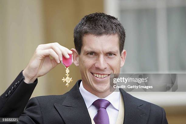 British tennis player Tim Henman poses with the OBE that he received from HM Queen Elizabeth II during investitures, for his services to lawn Tennis...