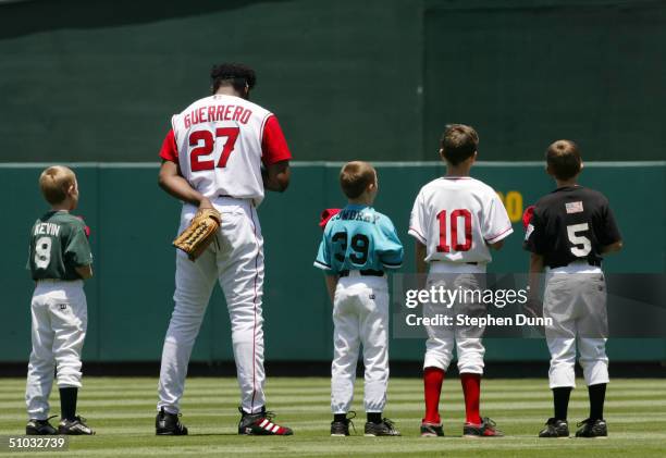 Vladimir Guerrero of the Anaheim Angels stands for the national anthem with young ball players before the game against the Chicago Cubs on June 13,...