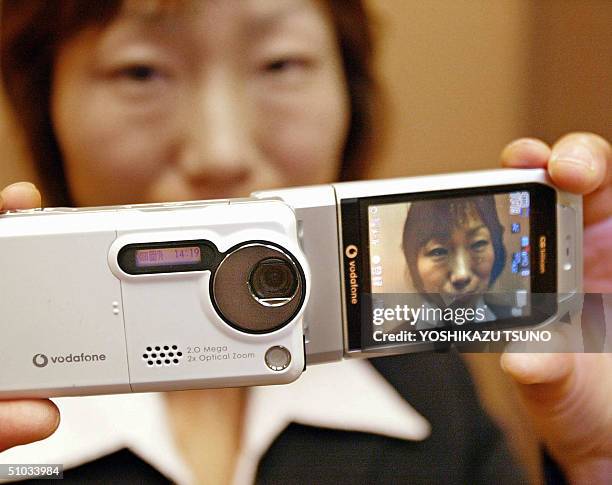 Japan's electronics giant Sharp employee Sachiko Senzai displays the company's latest mobile phone handset for Vodafone "V602SH", equipped with 2.02...