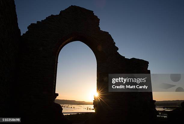 The winter suns rises over flood water still lingering in fields on the Somerset Levels viewed from Burrow Mump and the ruins of St Michael's church...