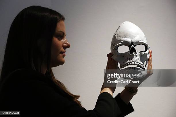 Member of staff poses with the mask from James Bond's Day of the Dead Costume, worn by Daniel Craig in Spectre, during a photocall at Christie's...