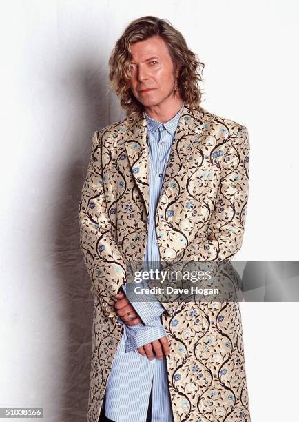 Musician David Bowie poses backstage at the Glastonbury festival, in a coat designed by Alexander McQueen, at Worthy Farm, Pilton on June 25, 2000 in...