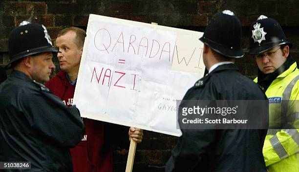 British police officers surround a protester holding a placard as the controversial Islamic cleric Yusuf Al-Qaradawi arrives at The London Central...