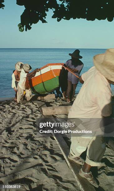 fisherman pulling a boat on shore - martinique beach stock pictures, royalty-free photos & images