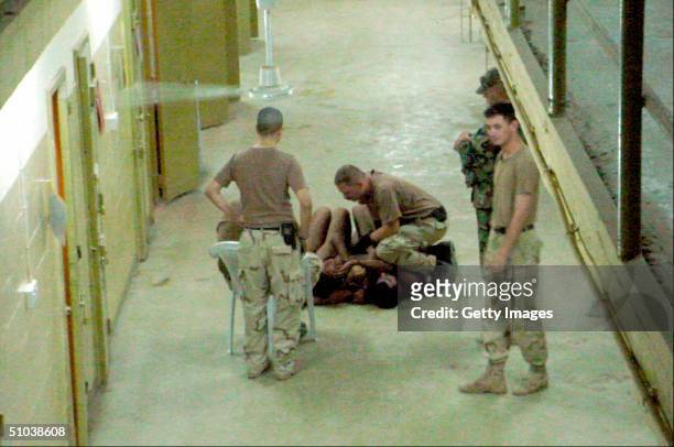 An unidentified U.S. Soldier at Abu Ghraib prison appears to be kneeling on naked detainees at the Abu Ghraib prison in these undated still photos....