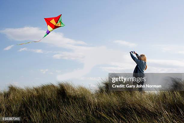 teenage girl flying a kite on the beach. - long grass bildbanksfoton och bilder