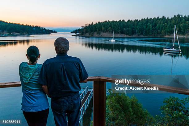 senior couple look across calm ocean bay, veranda - look back stockfoto's en -beelden