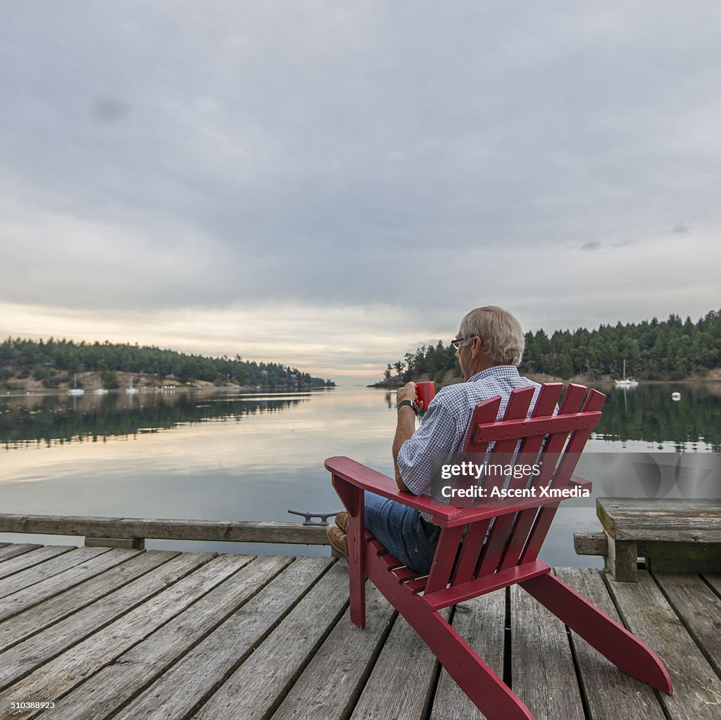 Senior man enjoys hot beverage, seaside veranda