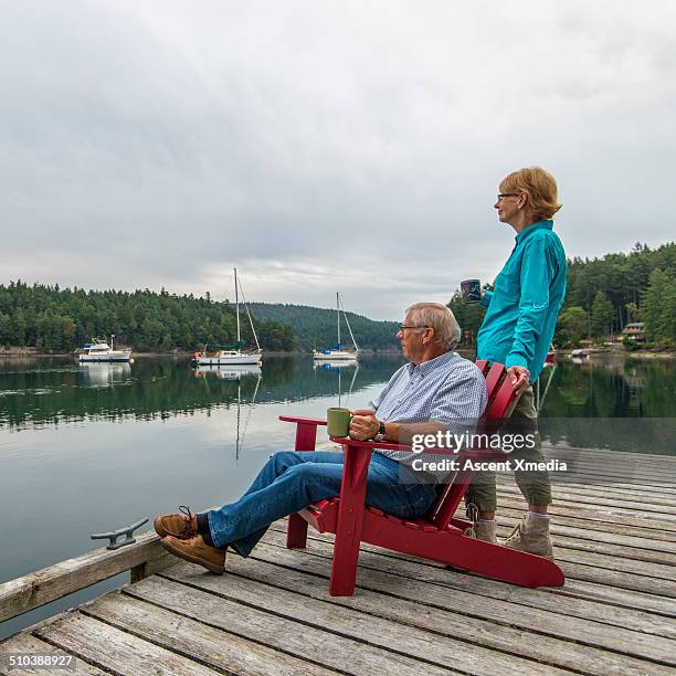senior couple look out across calm ocean bay, dawn - canadian pacific women stock pictures, royalty-free photos & images