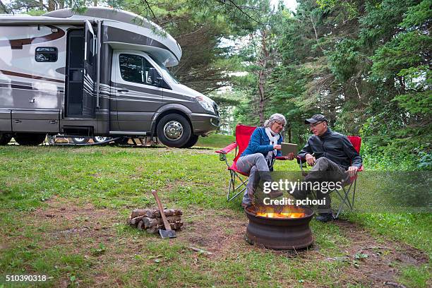 couple using digital tablet near campfire - campervan stockfoto's en -beelden